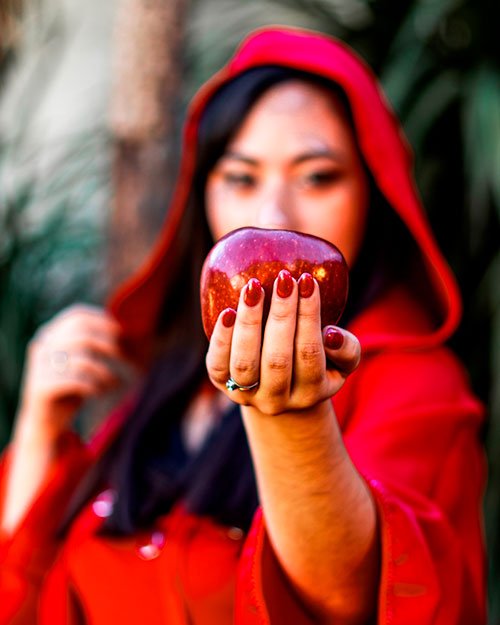 Retrato artístico inspirado en caperucita roja sosteniendo una manzana